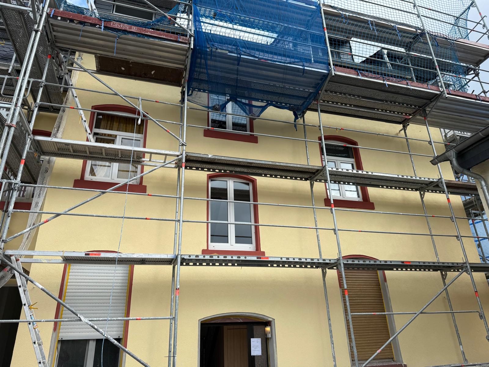 Altbaufassade in Creme mit rotbraun abgesetzten Fenstergewänden