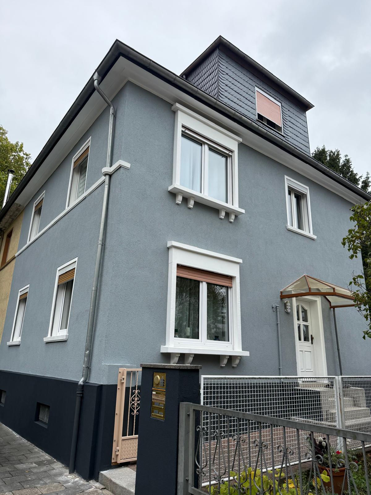 Sanierte Altbaufassade in Blaugrau mit weiß abgesetzten Fensterfaschen