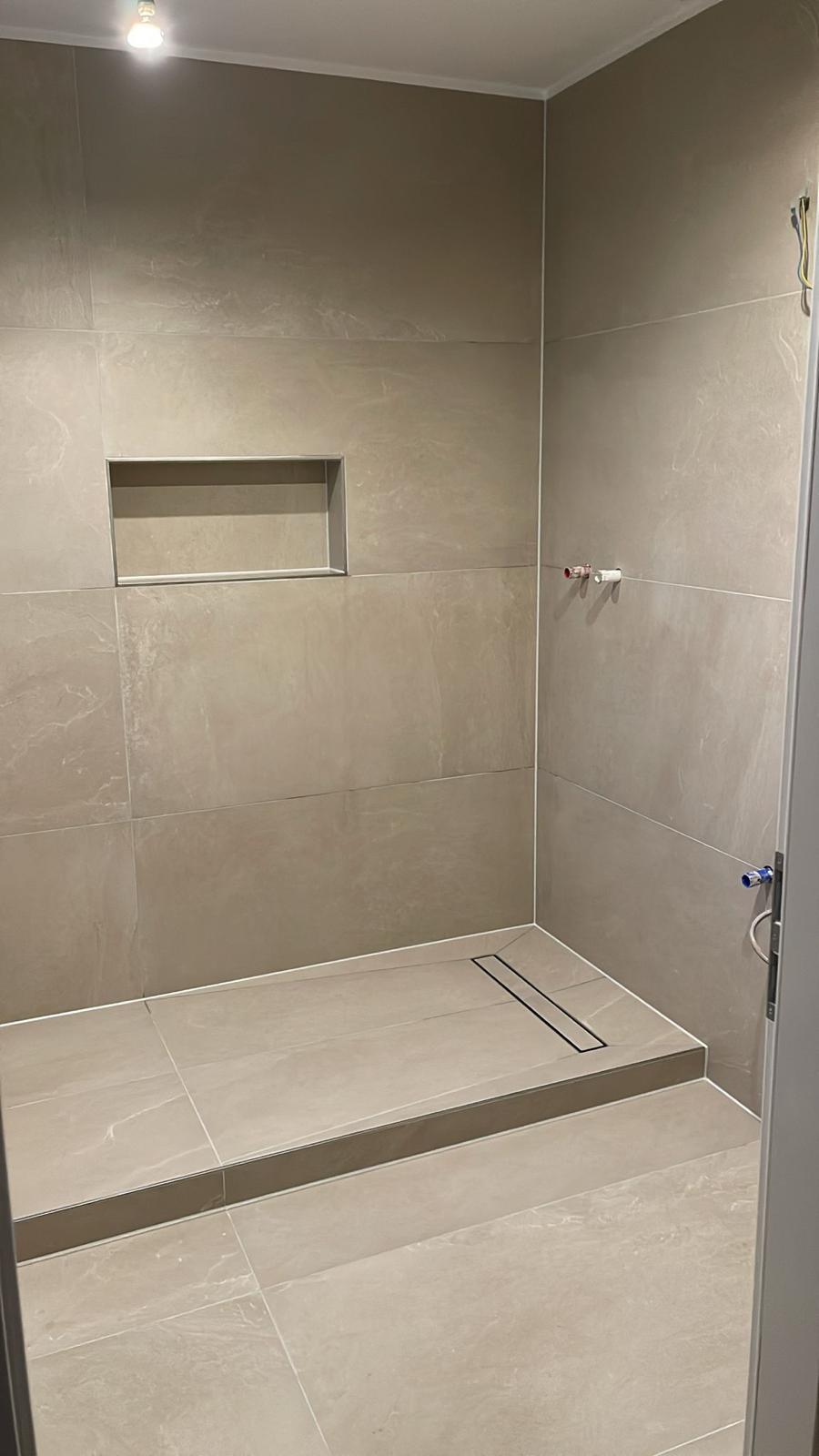 Fertig gefliestes Bad mit bodengleicher Dusche, Duschrinne und Wandnische