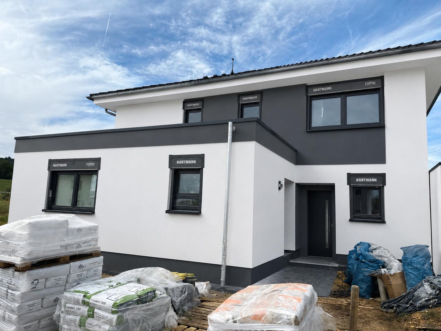 Derselbe Neubau fertig gedämmt und in Weiß und Anthrazit verputzt