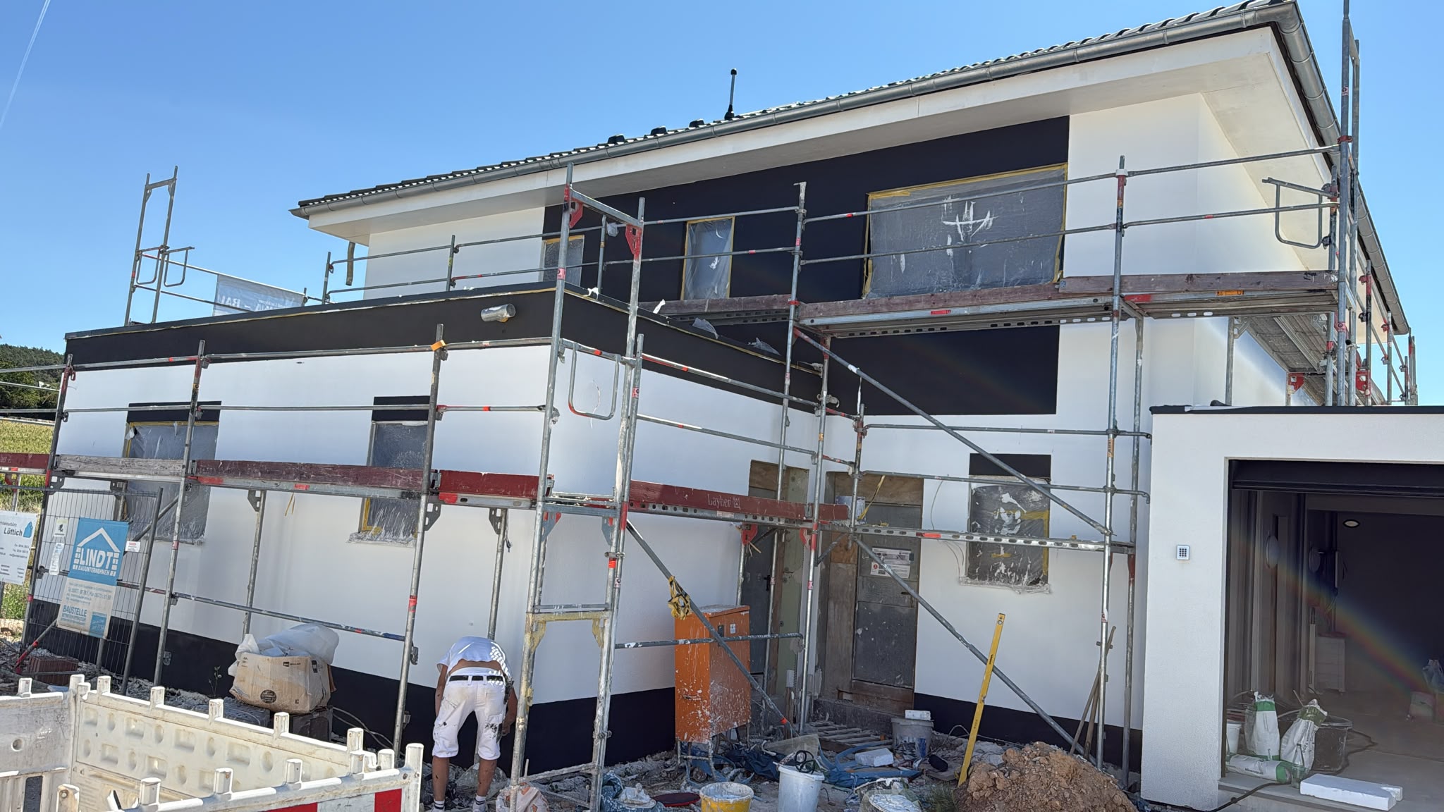 Neubaufassade mit weißen und anthrazitfarbenen Flächen, noch eingerüstet