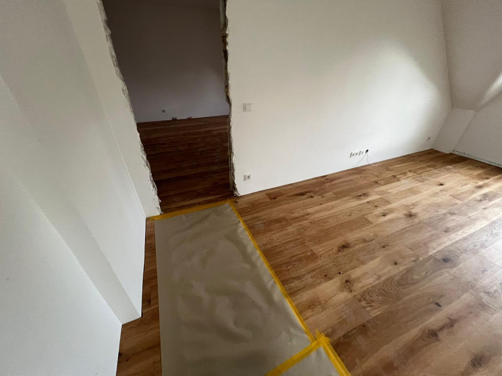 Übergang zwischen zwei Räumen mit verlegtem Eichenboden und Abdeckung auf der Treppe