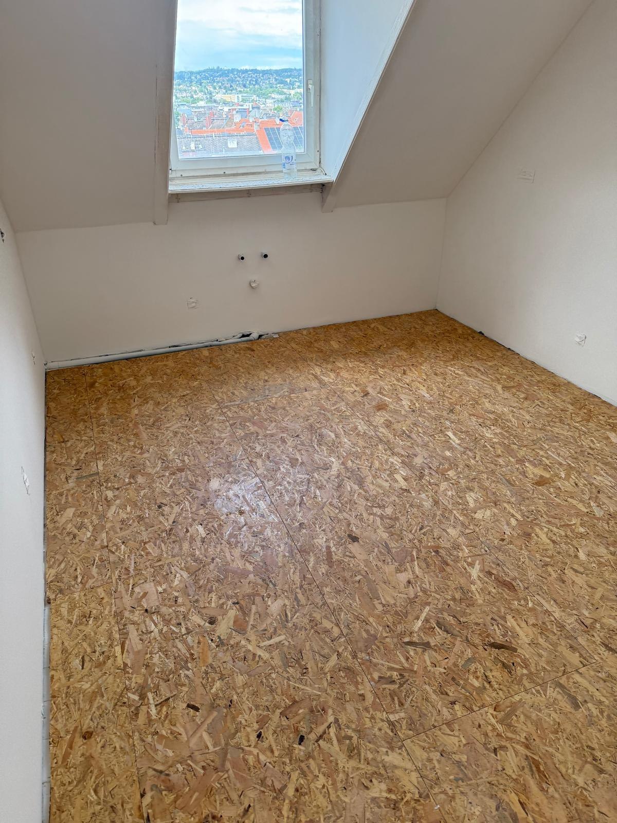 Zimmer mit fertig gestrichenen Wänden und Dachfenster