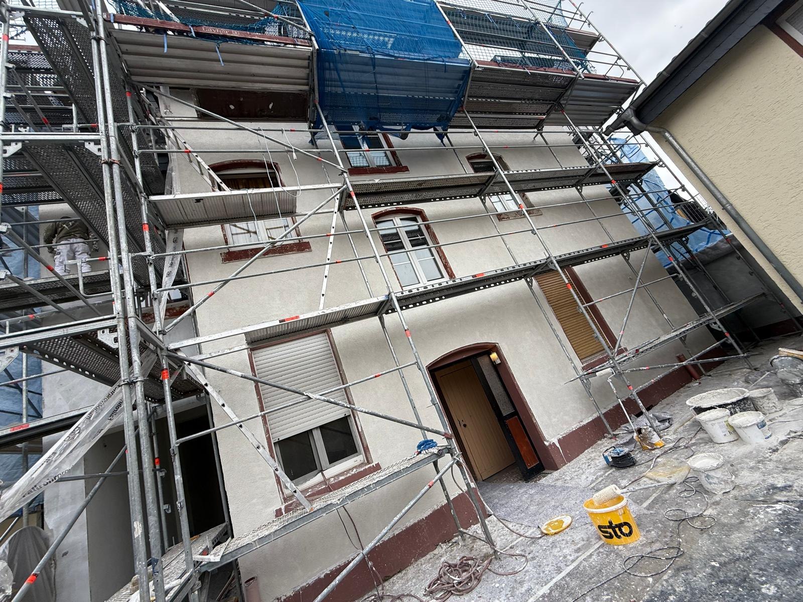 Fassade im Gerüst mit frisch aufgezogenem grauem Grundputz