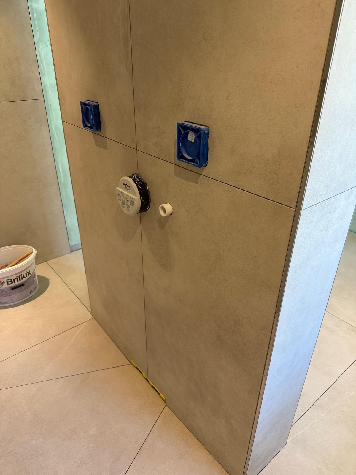 Eingehauste Vorwandinstallation mit blauen Anschlussstopfen und Grohe-Einbaukörper