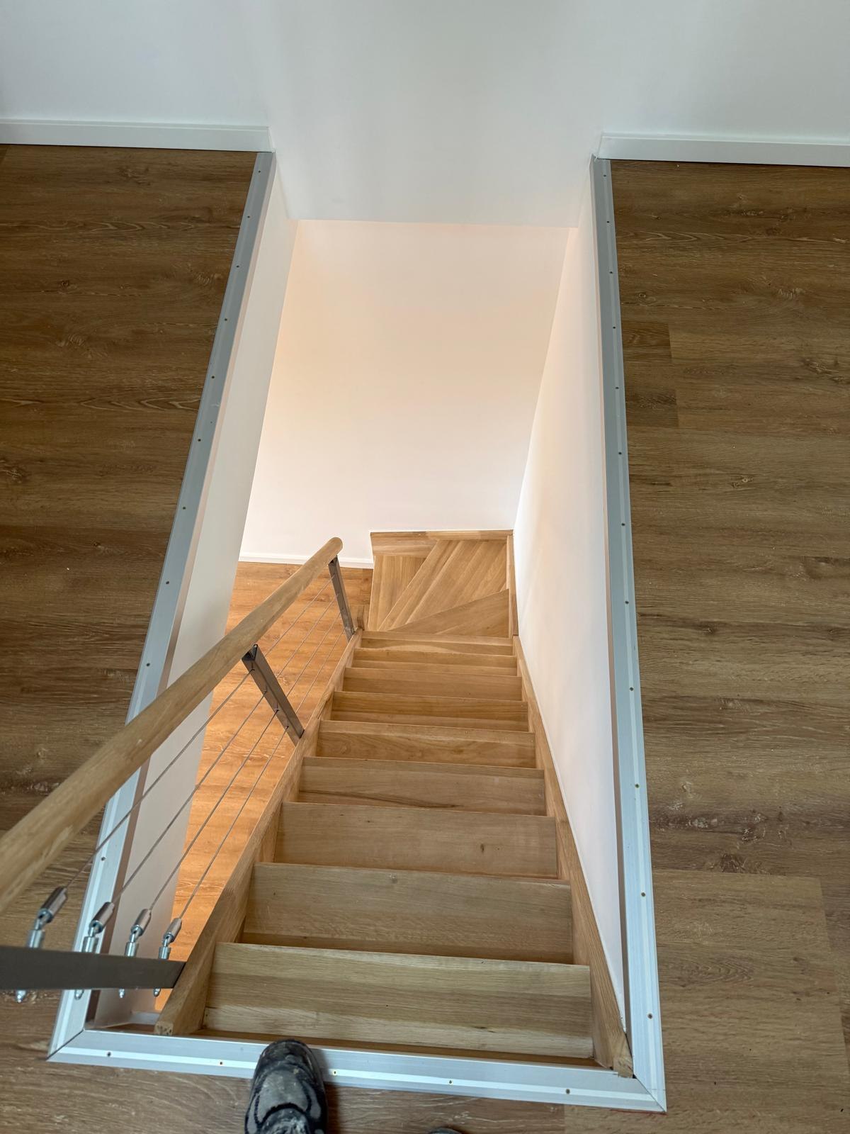 Blick von oben in die Treppenöffnung mit Eichentreppe und Vinylboden