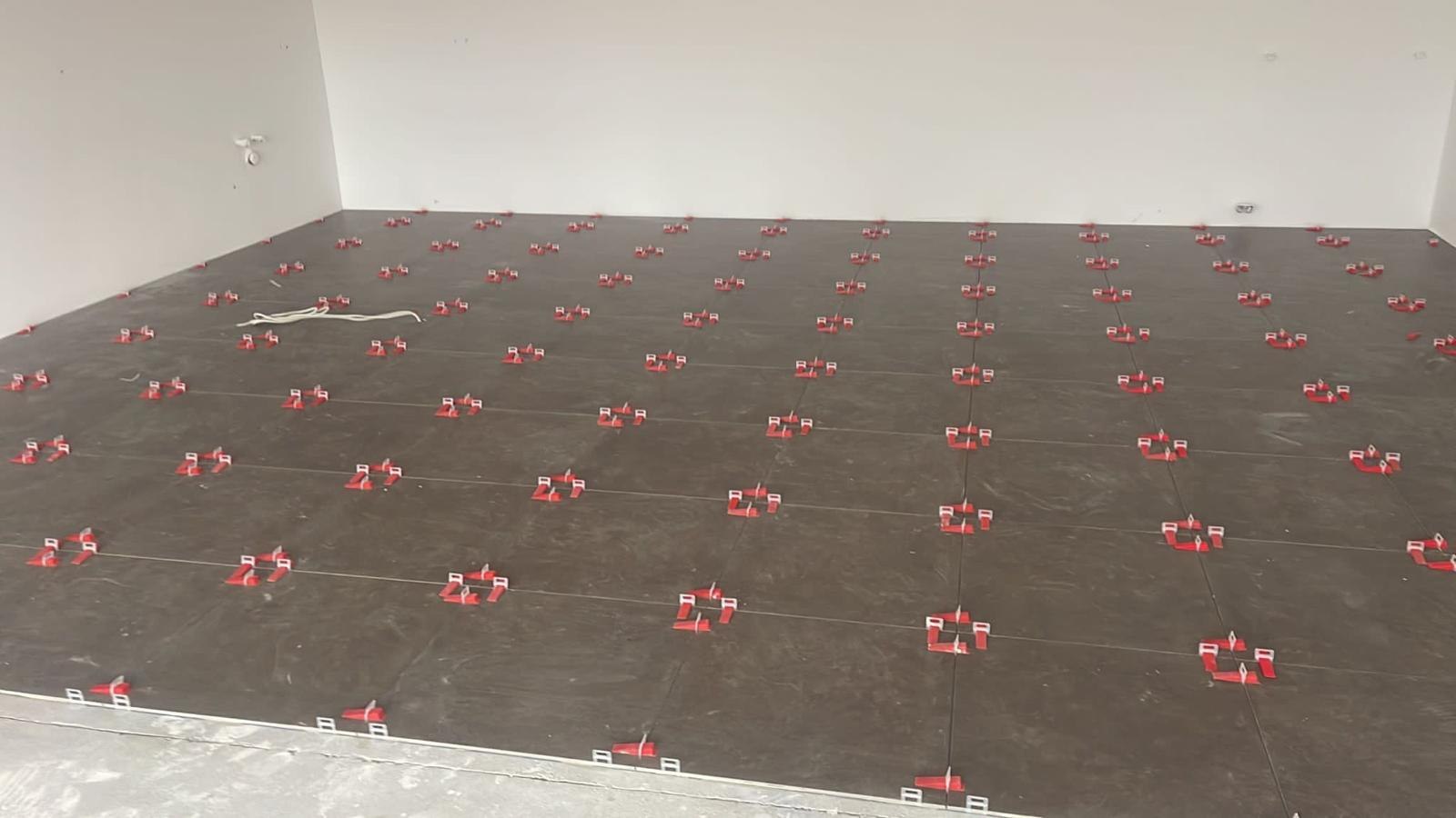 Großer Raum mit dunklen Großformatfliesen und roten Nivellierkeilen