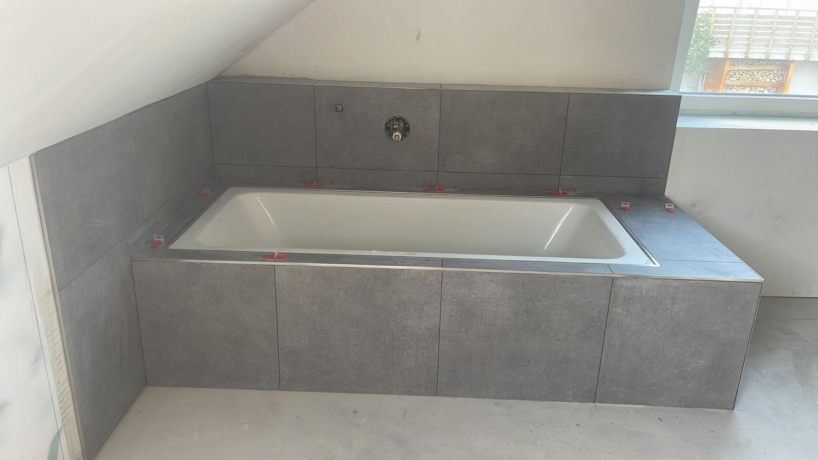 Eingefliste Badewanne unter der Dachschräge mit roten Nivellierkeilen