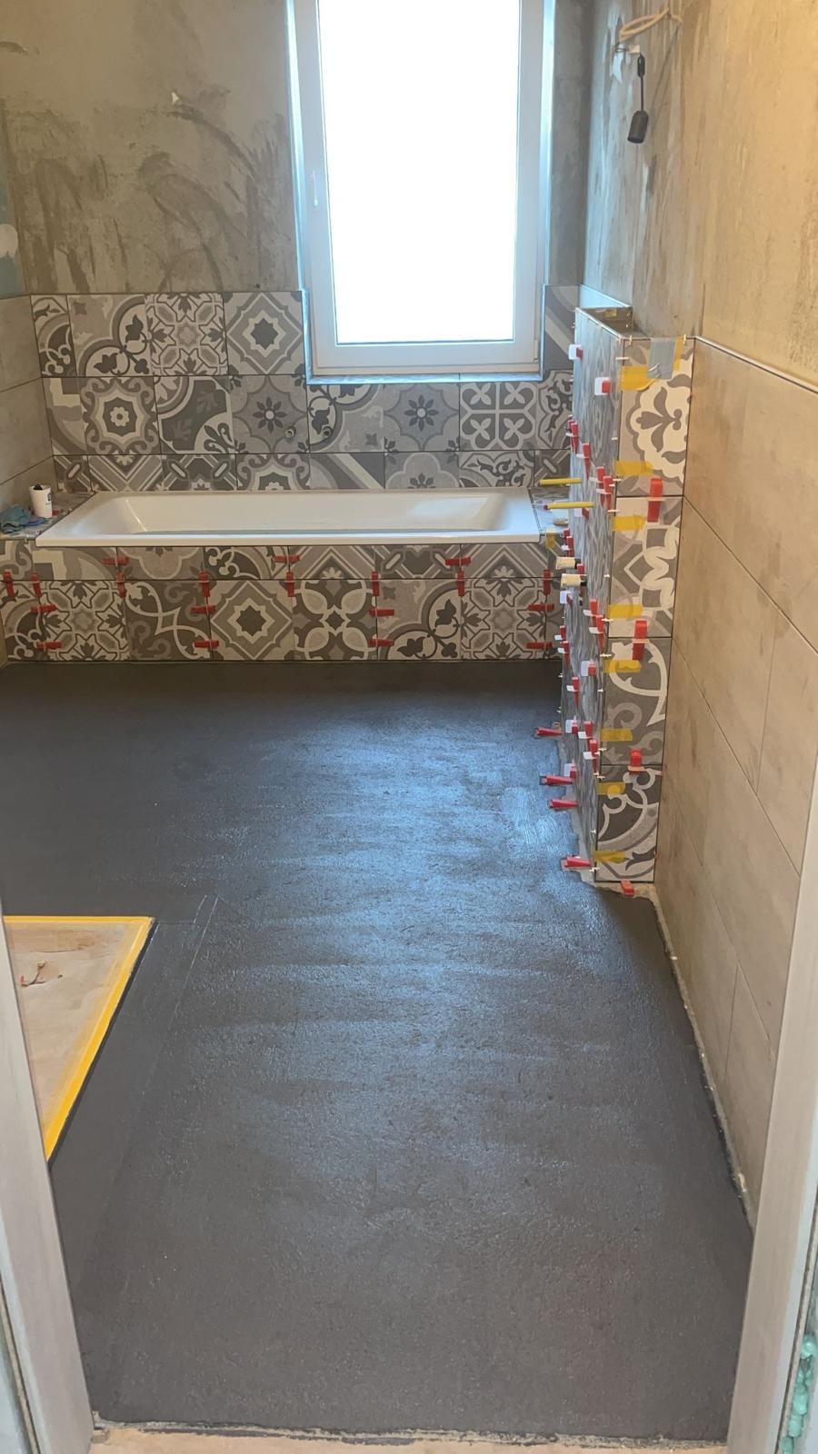 Bad mit grau gemusterten Retro-Fliesen an Wanne und Vorwand, Keile noch gesetzt
