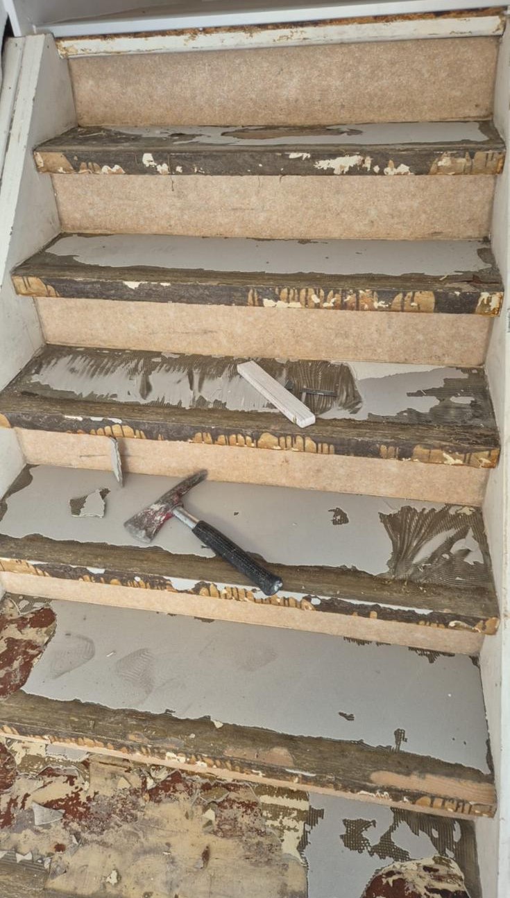 Stufen mit Kleberresten, Hammer und Spachtel liegen auf der Treppe