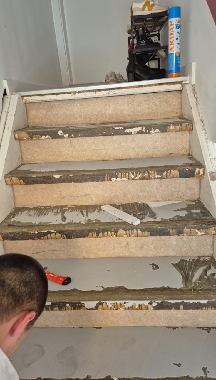 Mitarbeiter arbeitet am Treppenuntergrund, Reste und Werkzeug auf den Stufen